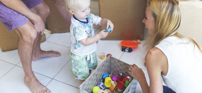 Criança guarda brinquedos numa caixa